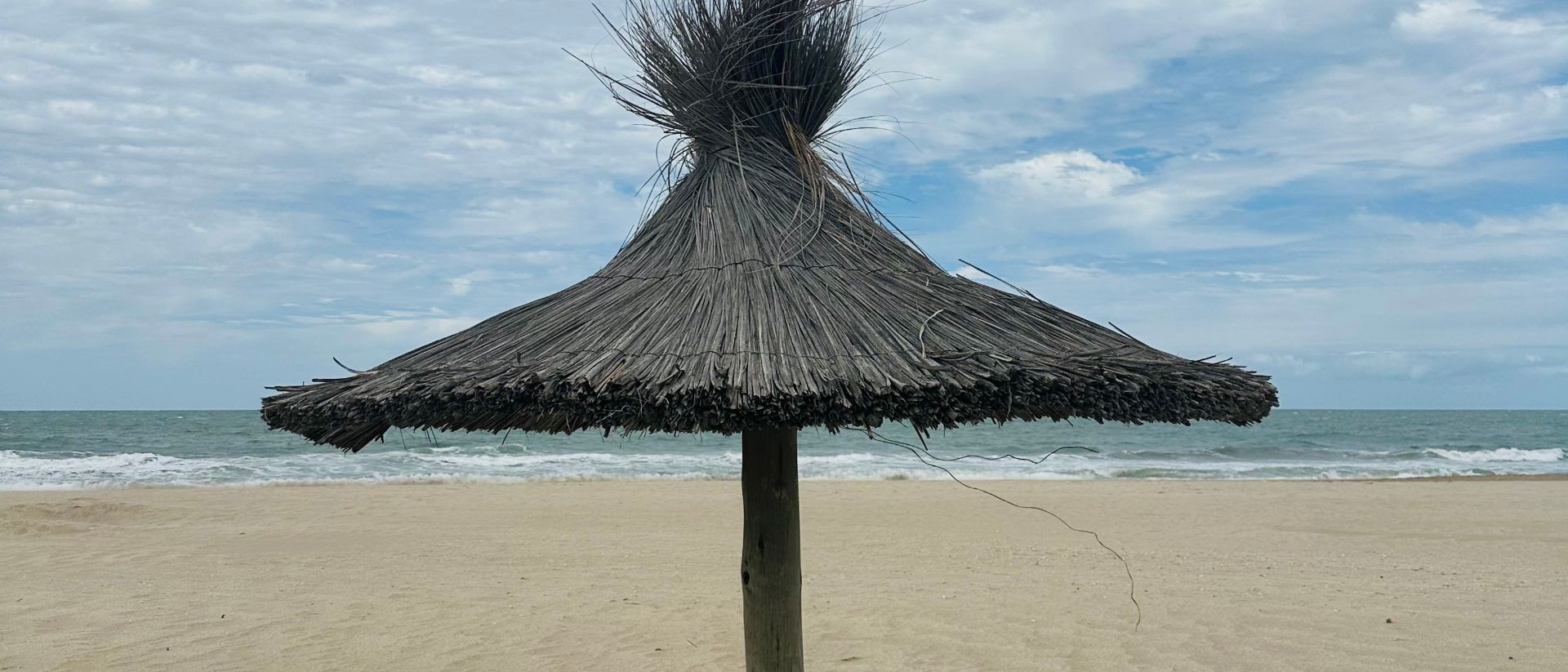 Sombrilla de paja en la playa de Las Gaviotas, con el mar de fondo
